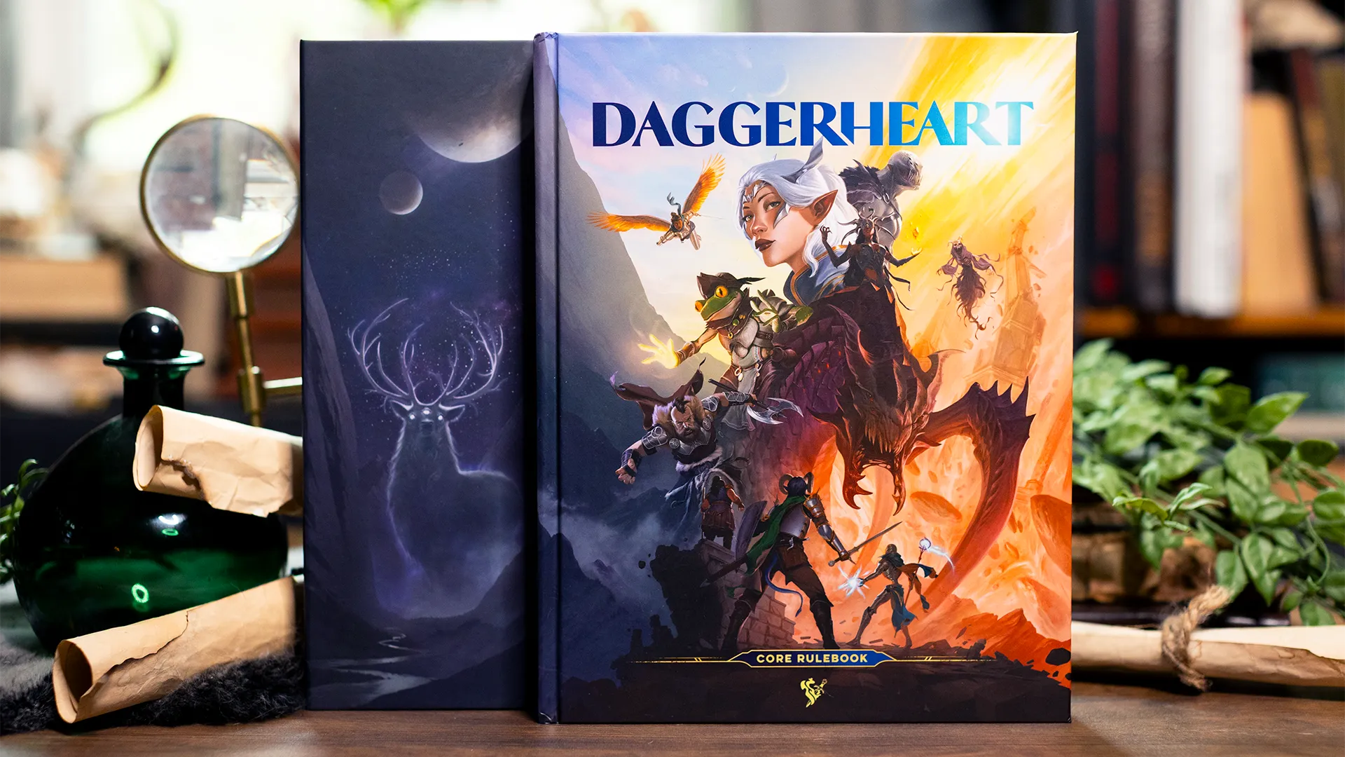 Two Daggerheart books lie on a wooden table. The left shows colorful fantasy heroes in action; the right features a glowing stag under a starry sky.